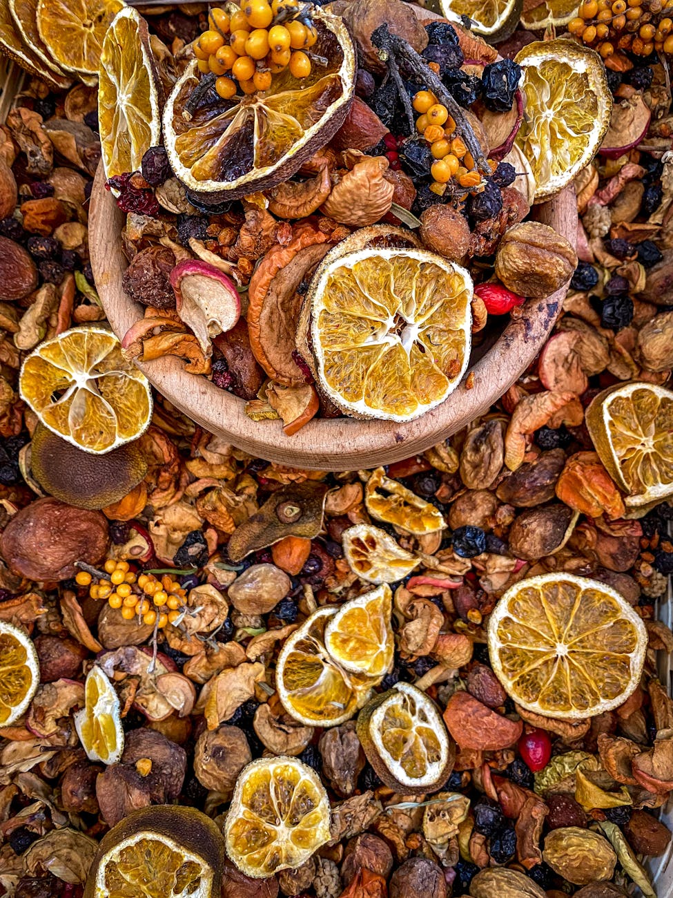 A colorful assortment of dried fruits including oranges, berries, and nuts displayed in a wooden bowl.
